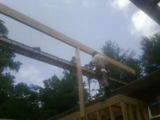 Carpenter setting a ridge beam over a new addition frame — Ice Dam Removal by Roofing Brothers in Cordesville