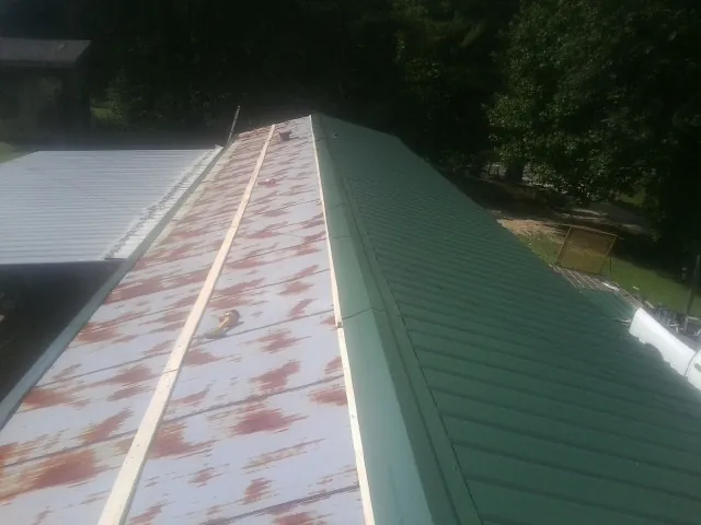 Old rusted panels beside newly installed green metal roofing — Wind Damage Roof Repair by Roofing Brothers in Cordesville