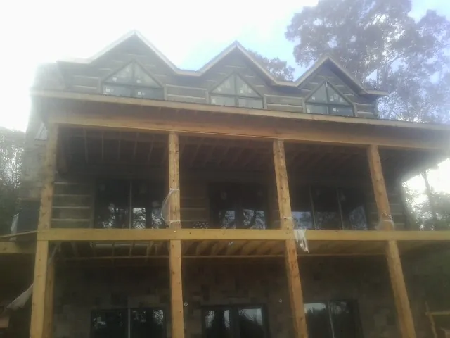 Dormers and porch framing on a large log home under construction — Roof Coating work by our crew in Cordesville