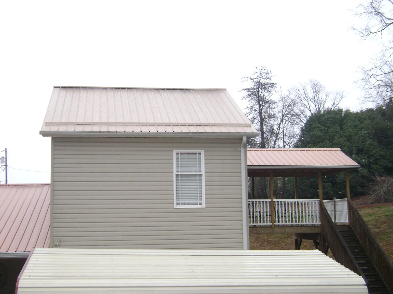 Tan metal roofs on a two story addition and attached porch, from a Roof Replacement job in Cordesville