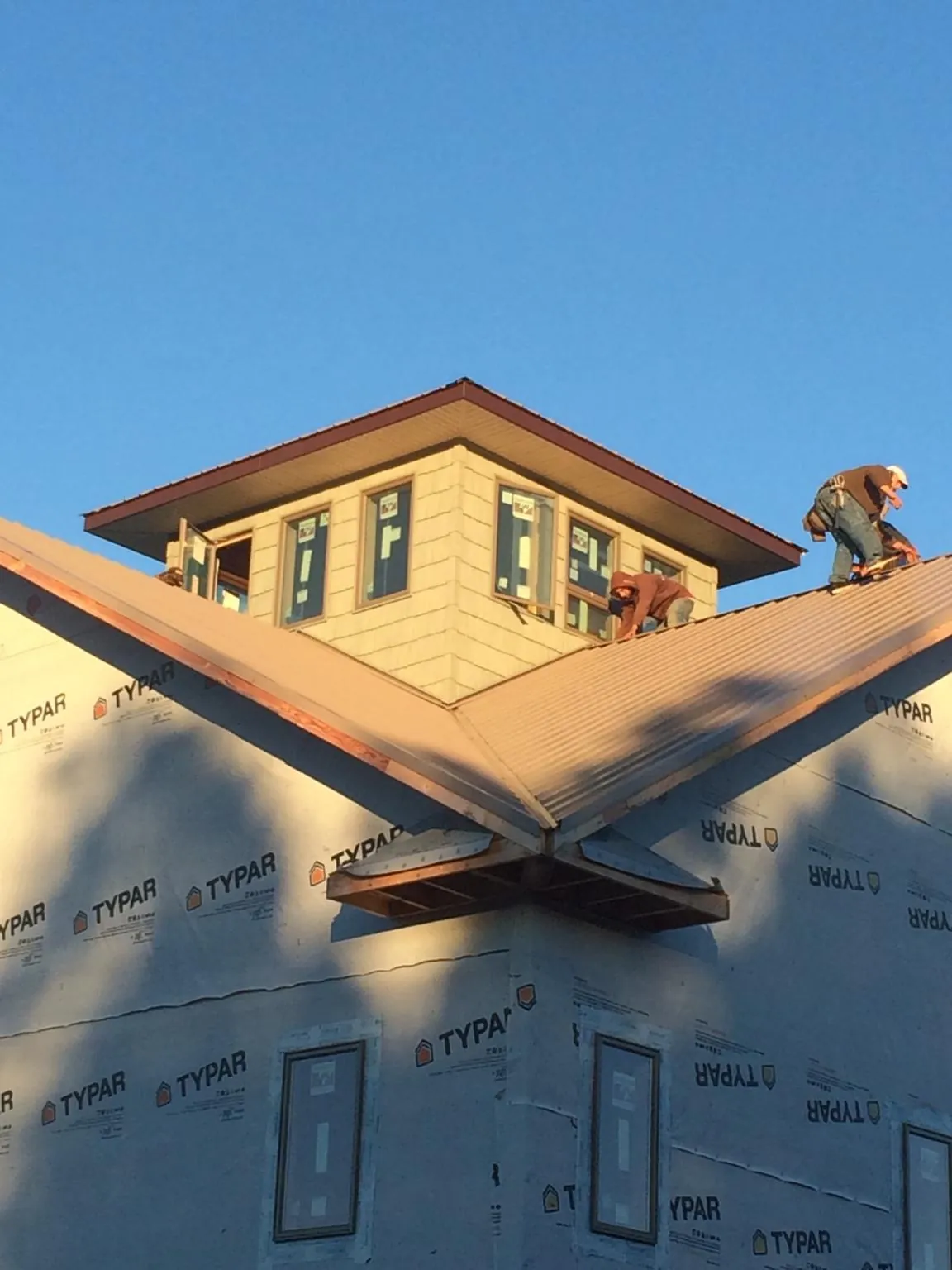 Roofers working around a rooftop cupola on a new metal roof at sunset — Roof Waterproofing in Cordesville by Roofing Brothers